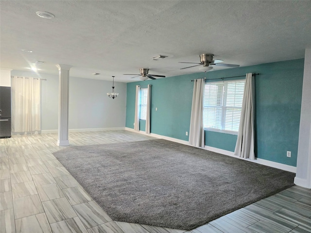 spare room with a healthy amount of sunlight, ornate columns, visible vents, and a textured ceiling