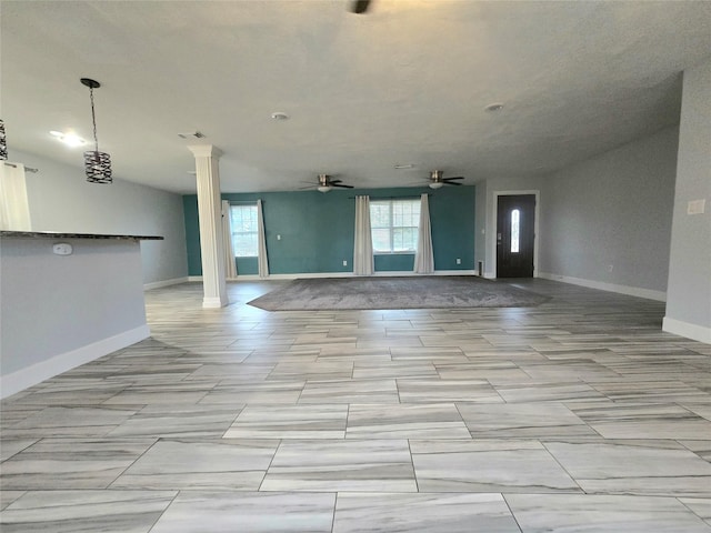 interior space with baseboards, visible vents, ceiling fan, and ornate columns