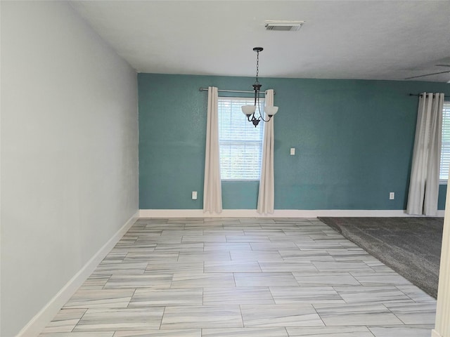 spare room with an inviting chandelier, visible vents, and baseboards