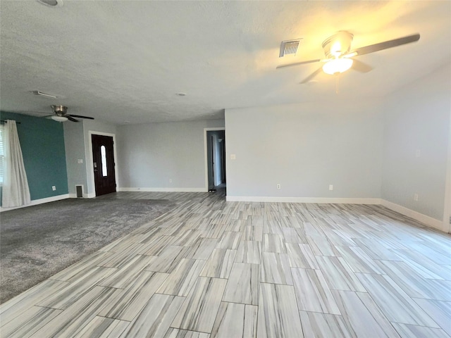 unfurnished room with baseboards, a textured ceiling, visible vents, and a ceiling fan