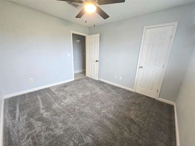 unfurnished bedroom with baseboards, visible vents, dark carpet, and a ceiling fan