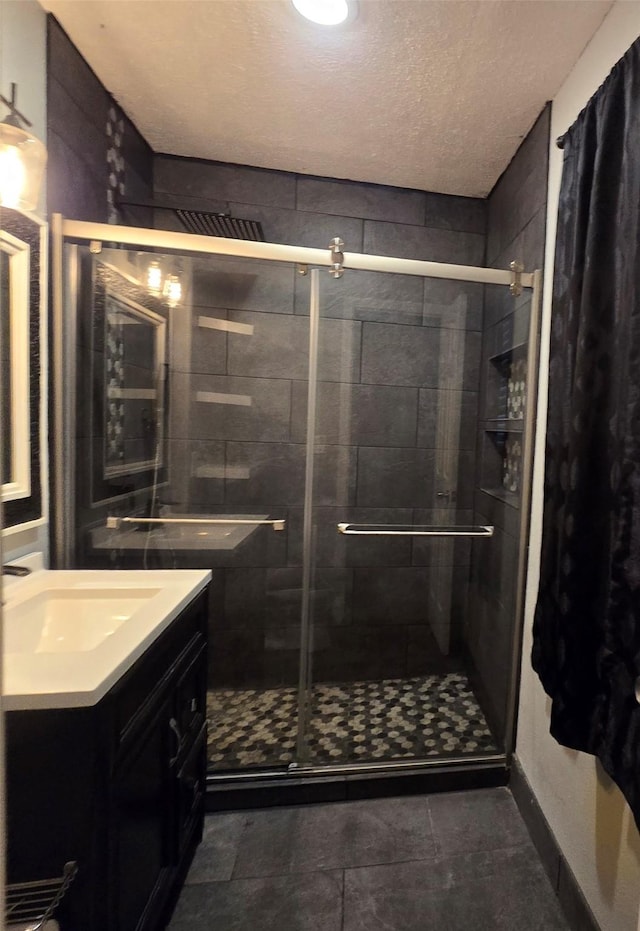 bathroom featuring a textured ceiling, a shower stall, and vanity