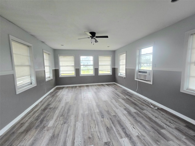 spare room featuring a ceiling fan, cooling unit, baseboards, and wood finished floors