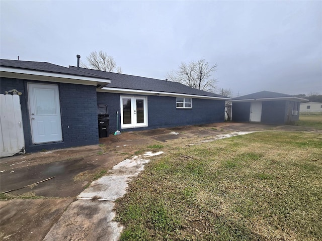 back of house featuring brick siding, a lawn, and french doors