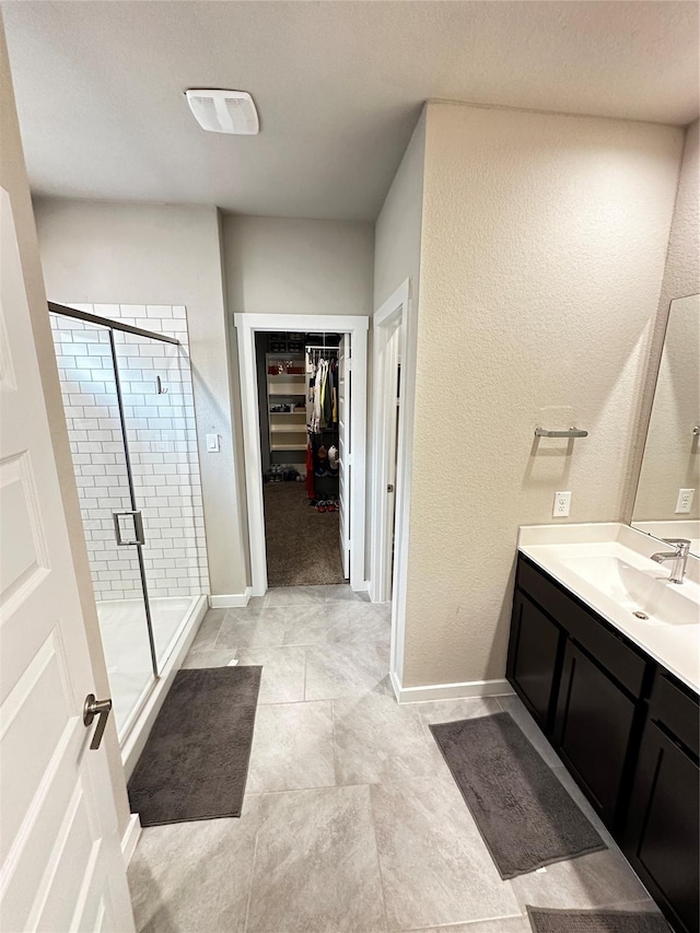 bathroom featuring a stall shower, baseboards, a spacious closet, and vanity