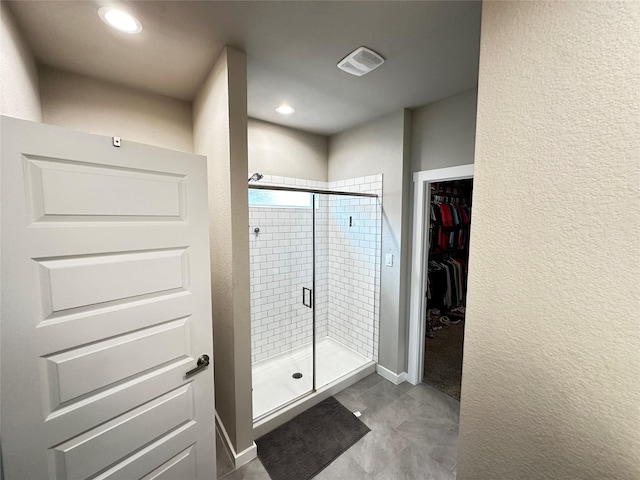 full bath featuring a textured wall, recessed lighting, visible vents, a shower stall, and a walk in closet