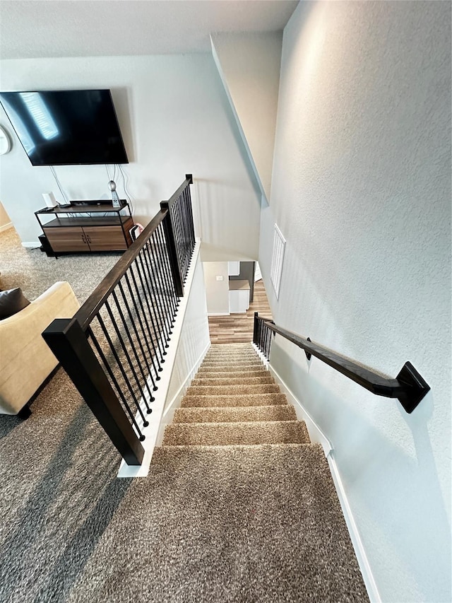 stairway with a textured wall and baseboards