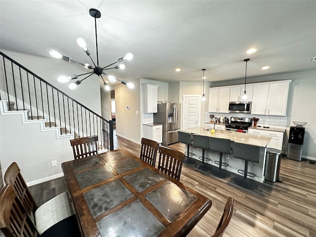 dining space with recessed lighting, dark wood-style flooring, baseboards, stairway, and an inviting chandelier