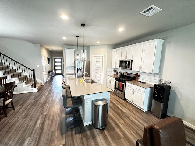 kitchen featuring decorative light fixtures, visible vents, appliances with stainless steel finishes, white cabinets, and a sink