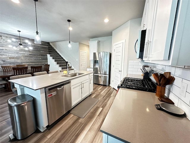 kitchen featuring stainless steel appliances, a sink, a center island with sink, and pendant lighting