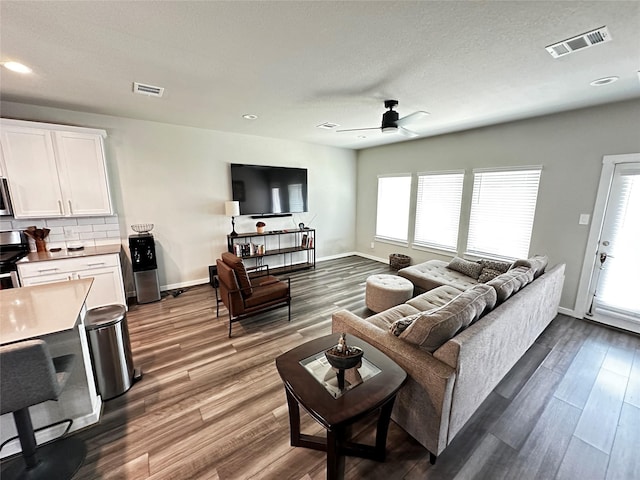 living area with baseboards, visible vents, and wood finished floors