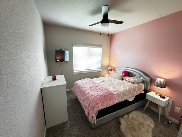 bedroom with baseboards, dark colored carpet, a ceiling fan, and a textured wall