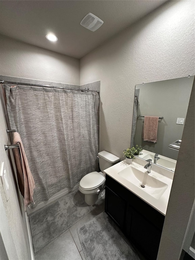 bathroom featuring visible vents, a textured wall, toilet, vanity, and tile patterned floors