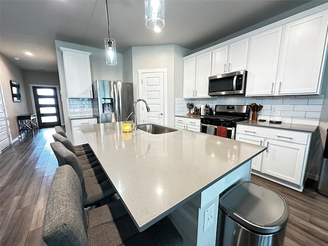 kitchen featuring stainless steel appliances, a sink, a center island with sink, and a breakfast bar area