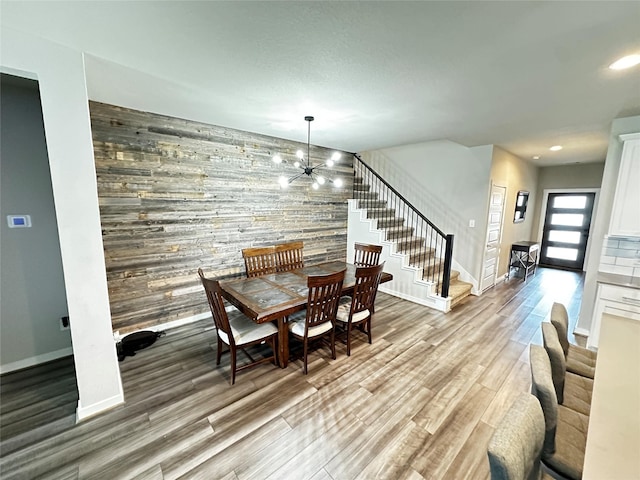 dining room featuring recessed lighting, light wood-style flooring, an accent wall, baseboards, and stairs