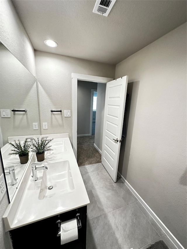 bathroom with double vanity, baseboards, visible vents, a textured ceiling, and a sink