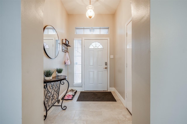 entrance foyer with light tile patterned floors, baseboards, and a wealth of natural light