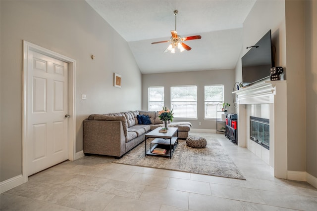 living area featuring lofted ceiling, ceiling fan, a fireplace, and baseboards