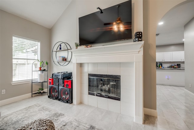 interior space featuring light tile patterned floors, baseboards, a tiled fireplace, lofted ceiling, and recessed lighting