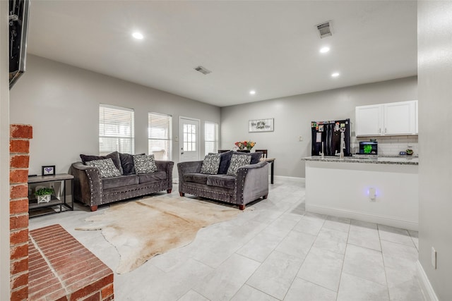 living room featuring light tile patterned flooring, baseboards, visible vents, and recessed lighting