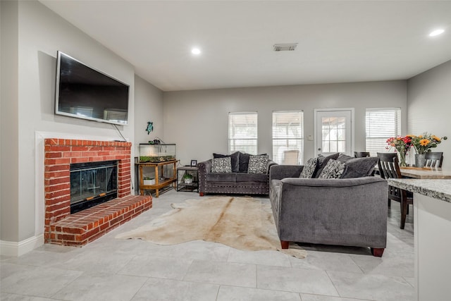 living area with a brick fireplace, light tile patterned floors, visible vents, and recessed lighting