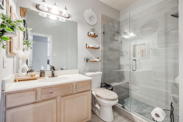 bathroom featuring a shower stall, toilet, and vanity