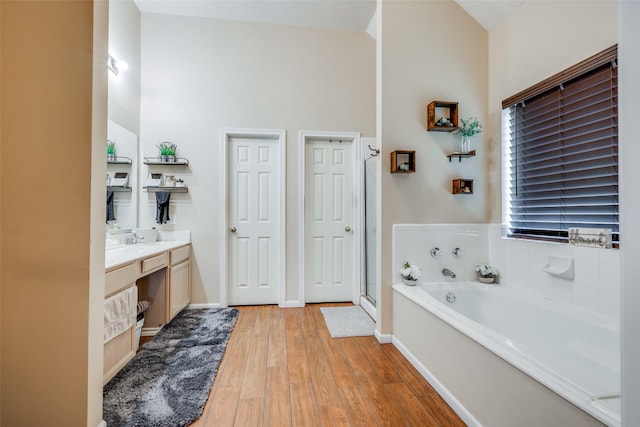 full bathroom with baseboards, wood finished floors, a garden tub, vanity, and a shower stall