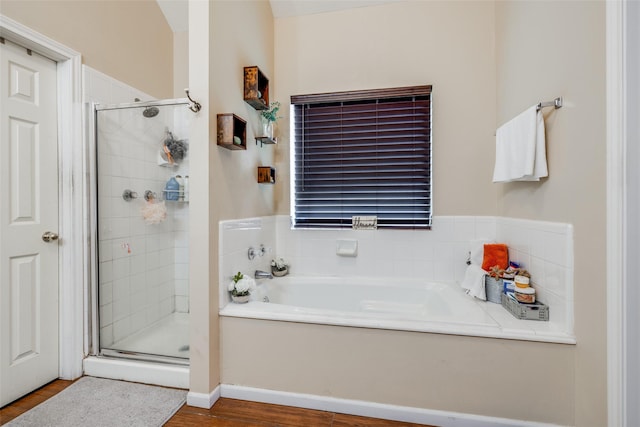 bathroom featuring a garden tub, a shower stall, and wood finished floors