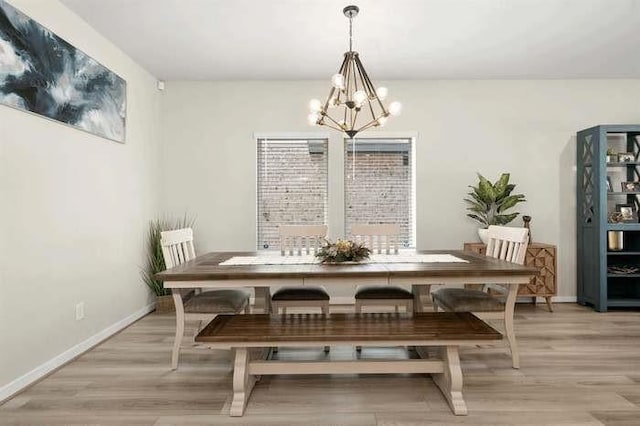 dining area featuring a chandelier, light wood finished floors, and baseboards