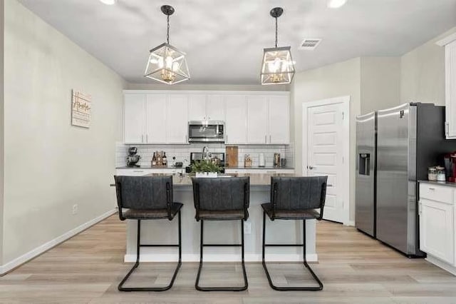 kitchen with hanging light fixtures, white cabinetry, visible vents, and appliances with stainless steel finishes