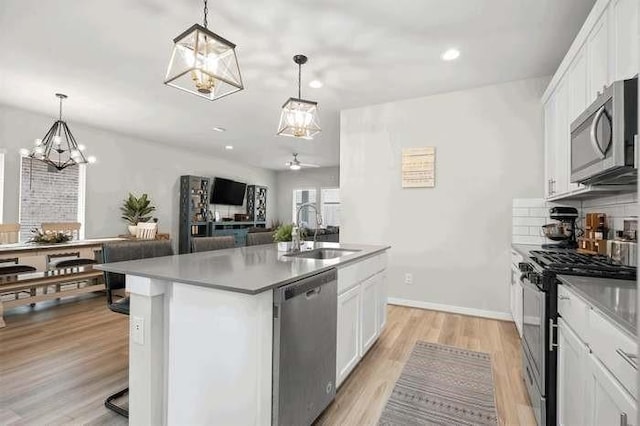 kitchen with a kitchen island with sink, appliances with stainless steel finishes, a sink, and white cabinetry