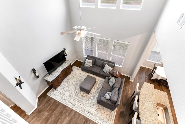 living room featuring dark wood-style floors, plenty of natural light, baseboards, and a ceiling fan