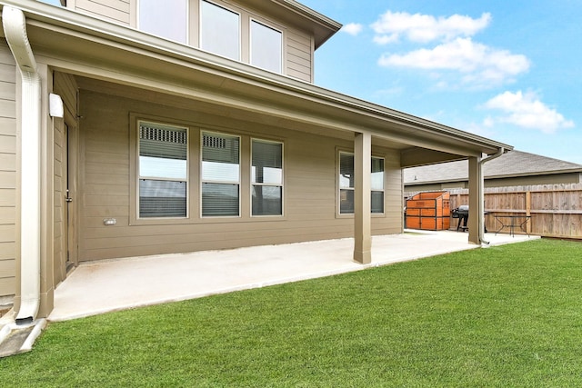 back of property with fence, a lawn, and a patio