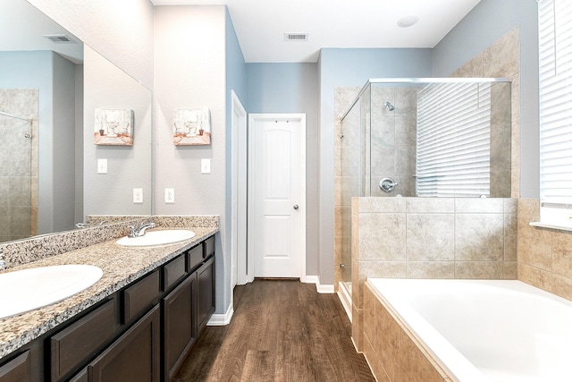 full bath featuring visible vents, a sink, a garden tub, and wood finished floors