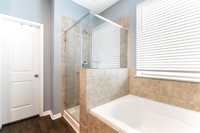 full bath with wood finished floors, a stall shower, and a garden tub