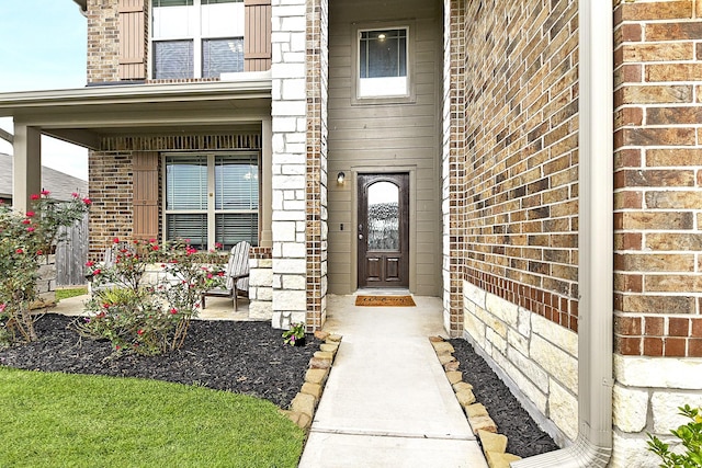 entrance to property featuring covered porch and brick siding