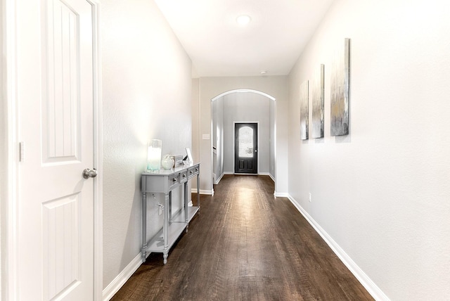 doorway featuring dark wood-style floors, baseboards, and arched walkways