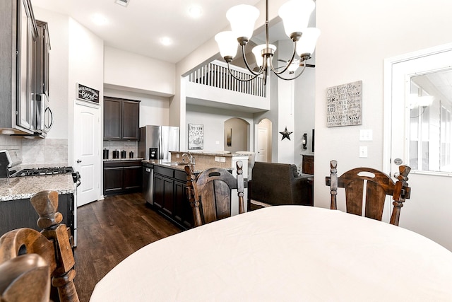 dining space featuring arched walkways, a towering ceiling, visible vents, dark wood finished floors, and an inviting chandelier