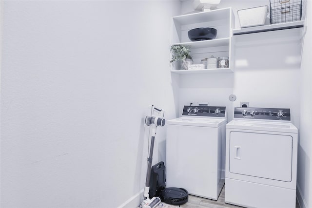 laundry area with washing machine and clothes dryer, light wood-style floors, laundry area, and baseboards