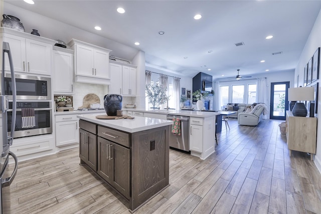 kitchen featuring white cabinets, light countertops, a ceiling fan, stainless steel appliances, and a kitchen island