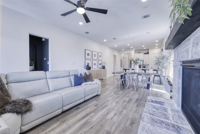 living room featuring light wood-style floors, a ceiling fan, visible vents, and recessed lighting