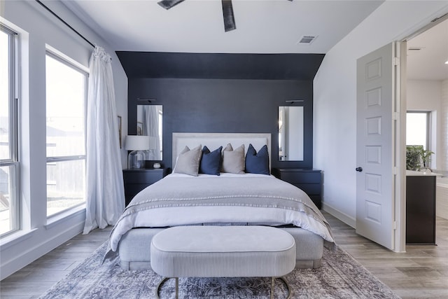 bedroom with light wood finished floors, visible vents, baseboards, and a ceiling fan