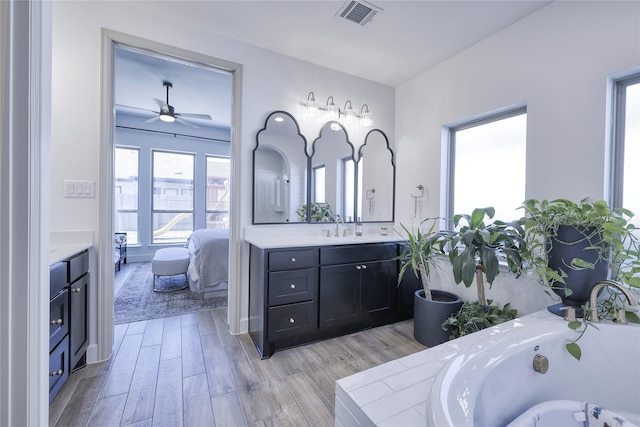bathroom featuring a tub, ceiling fan, ensuite bathroom, vanity, and visible vents