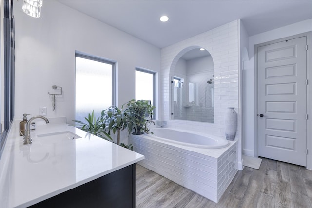 bathroom with tiled shower, vanity, a garden tub, and wood finished floors