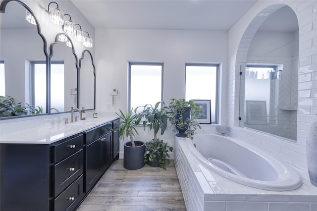 full bath featuring a bath, vanity, and wood finished floors