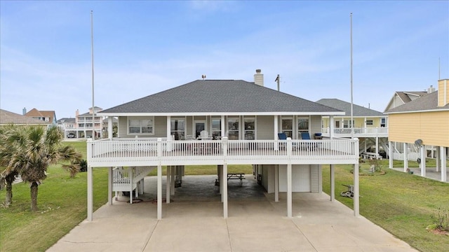 rear view of property with a carport, roof with shingles, a porch, and a lawn