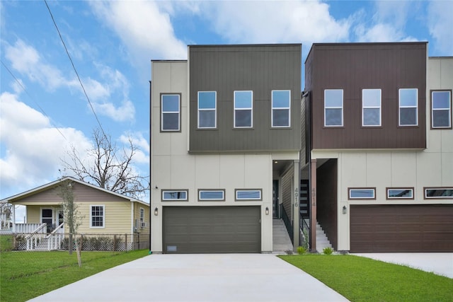 contemporary house with driveway, stairs, a garage, and a front lawn