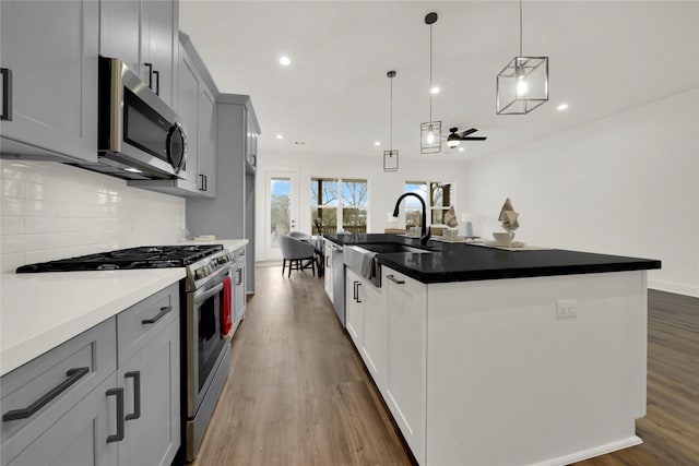 kitchen with a sink, decorative backsplash, recessed lighting, appliances with stainless steel finishes, and dark wood-style flooring