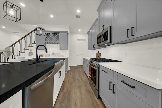 kitchen featuring visible vents, gray cabinets, a sink, dark wood-style floors, and stainless steel appliances