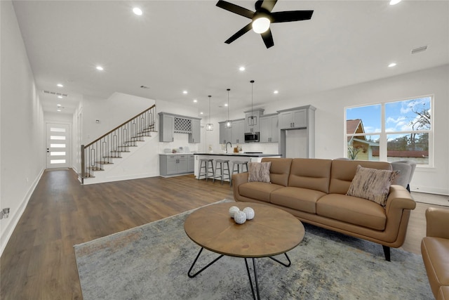 living area with stairway, visible vents, dark wood finished floors, recessed lighting, and ceiling fan